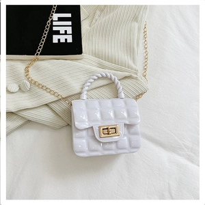 Close-up of white quilted jelly bag with gold chain strap on a soft knitted background