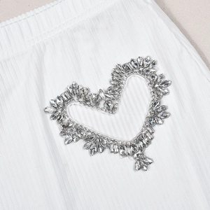 Detail eines silbernen Herz-Strass-Patches auf weißem Rippstrickgewebe für Damenmode