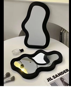 Modern minimalist irregular wave-shaped vanity mirror with a sleek black resin frame
