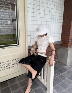 Camicetta bianca con maniche a sbuffo abbinata a pantaloncini neri per un look casual
