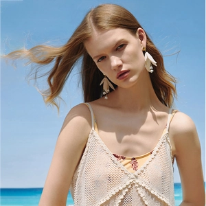 Elegant white lily of the valley earrings on a model against a sunny beach background