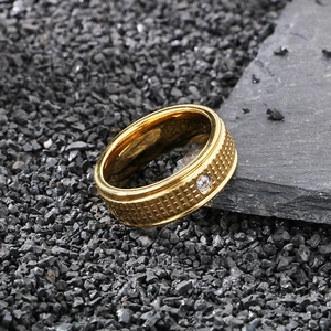 Macro shot of gold grid embossed pattern and clear zircon inlay on stainless steel ring