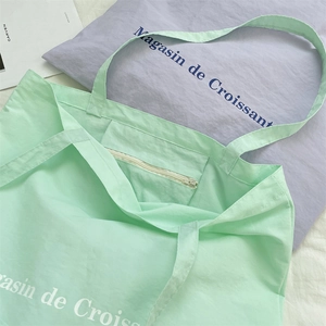 Detail of mint green canvas tote bag featuring a zipped inner pocket and artistic print