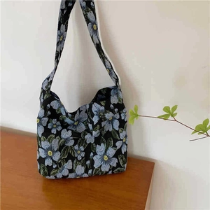 Detail of floral tote bag with blue petals on black canvas and wide shoulder strap