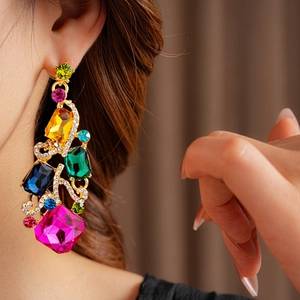 Detailed view of vintage gold earrings with large colorful gemstones and crystals on model