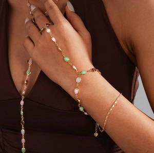 Close-up of gold chain hand bracelet with oval colorful resin stones on a model