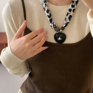 Close-up of heart pendant necklace with leopard print scarf chain on a model neck
