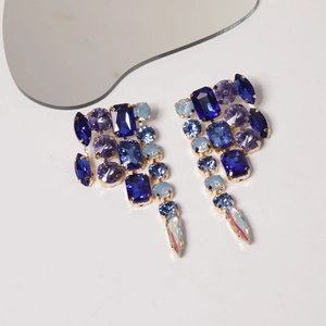 Detail of luxury teardrop tassel earrings with blue and purple crystals and gold metal