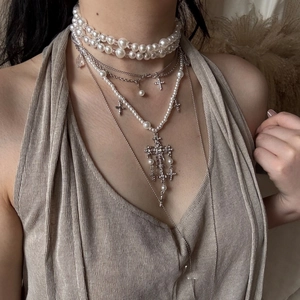Close-up of layered baroque pearl choker and ornate rhinestone cross pendant necklaces