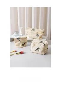 Detailed set of three embroidered cotton linen makeup bags with green leaf patterns