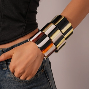 Macro shot of chunky acrylic geometric bangle with black, white, gold and amber tones
