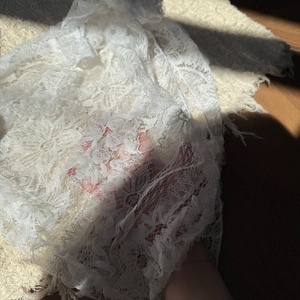 Detailed close-up of white floral lace fabric texture for bikini swimsuit cover-up