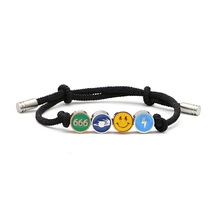 Close-up of black braided bracelet with smile and lightning bolt metal charms