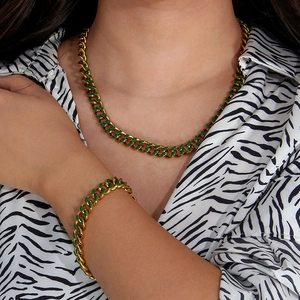 Close-up of golden Cuban link necklace and bracelet set with green enamel accents on a model