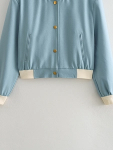 Detail of blue bomber jacket with cream ribbed hem and gold metallic snap buttons