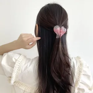 Detail view of pink heart hair claw clip styled on a model's half-up hairstyle