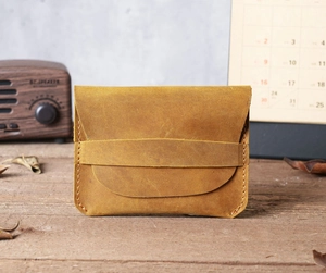 Detailed view of handmade tan crazy horse leather card holder on a wooden desk