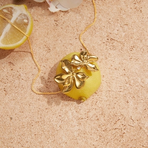 Detail view of gold floral pendant necklace with zircon accent on stone background