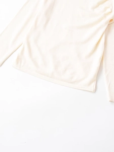 Detailed macro view of the cream white wool knit top hem and fabric texture