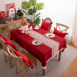 Red Christmas reindeer jacquard tablecloth with festive tassels on a wooden dining table