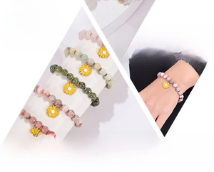 Detail of pink zebra stone beaded bracelet with yellow sunflower pendant on wrist