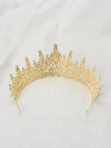 Close-up of golden princess crown with green and clear rhinestones on white fabric