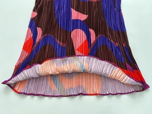 Macro detail of pleated hem showing colorful geometric patterns and rolled edge stitching