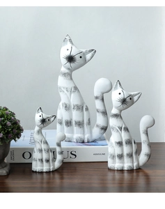 Detailed view of three ceramic cat figurines with minimalist stripes on a wooden surface