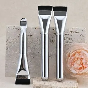 Detailed view of silver metal makeup brushes with black fiber bristles and a spatula tip