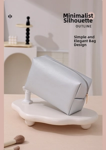 Detailed view of silver PU cosmetic bag with cross-grain texture on a white tray