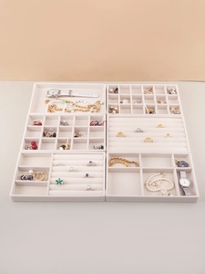 Detailed top view of four beige velvet jewelry organizer trays with diverse compartments