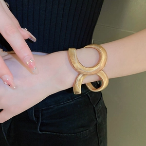 Polished gold metal snake spiral cuff bracelet in an oversized minimalist fashion style