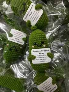 Detail view of bulk packaged handmade crochet emotional support pickle dolls with cards