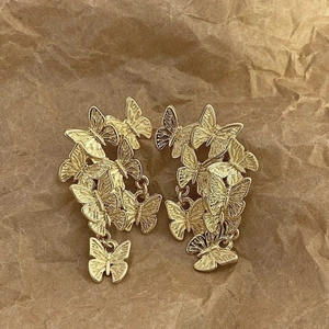 Macro shot of layered gold butterfly dangle earrings on a textured vintage paper background
