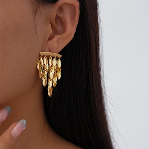 Close-up of golden leaf tassel earrings with polished metallic sequins and layered design