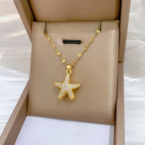 Macro view of gold starfish pendant with white crystal pavé in a champagne satin jewelry box