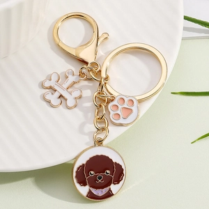 Detailed view of a golden keychain with Poodle, bone, and pink paw print enamel charms