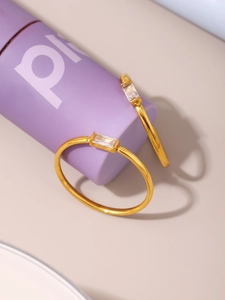 Detail of two gold rings with rectangular zircon stones on a purple display stand