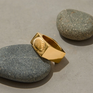 Gros plan d'une bague chevalière vintage en or 18k avec relief de coquillage sur pierre