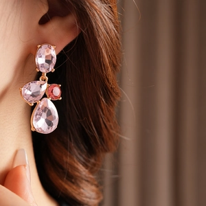 Close-up of vintage pink teardrop earrings with gold plating and red crystal accents