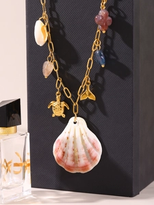 Detailed close-up of golden ocean necklace with shell, turtle, and whale tail charms