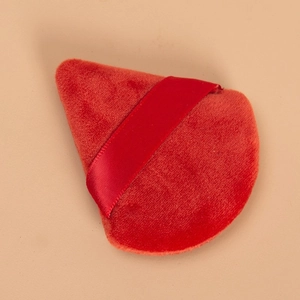 Dettaglio del piumino da cipria triangolare in velluto rosso con nastro di raso per trucco