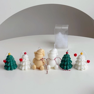 Mini Christmas tree and bear scented candles arranged on a minimalist white table