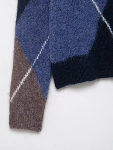 Macro shot of argyle knit sweater detail with navy and grey geometric pattern