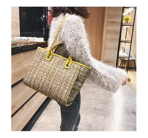Detail of checkered tweed bucket bag with gold chain strap and leather handle handles