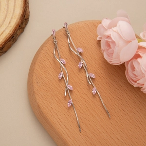 Detail of silver leaf tassel earrings with pink marquise gemstones on wooden base