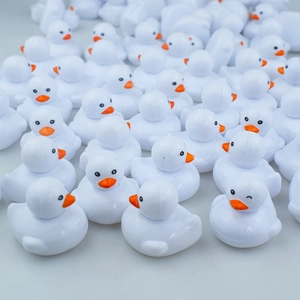 Close-up of mini white rubber ducks with orange beaks and one cute winking expression