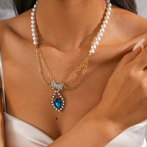 Close-up of pearl necklace with diamond bow and blue water drop gemstone pendant