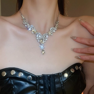 Close-up of sparkling teardrop and round crystal necklace set on elegant model wearing black