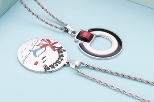 Detailed macro view of silver twist chain necklaces with enamel charms and red gemstone